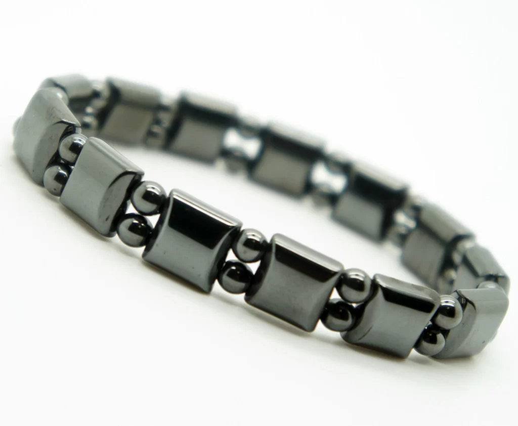 Black hematite magnetic bracelet with 9mm width, elastic band, and polished stone beads on male wrist beside a Bulova watch.