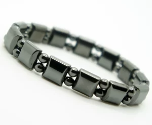 Black hematite magnetic bracelet with 9mm width, elastic band, and polished stone beads on male wrist beside a Bulova watch.