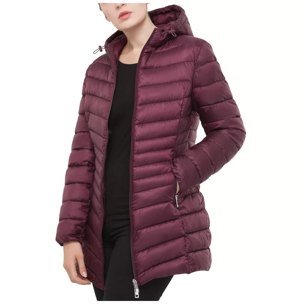 Slim-fit long black puffer jacket with hood, water-resistant and packable, worn by woman in city during winter.